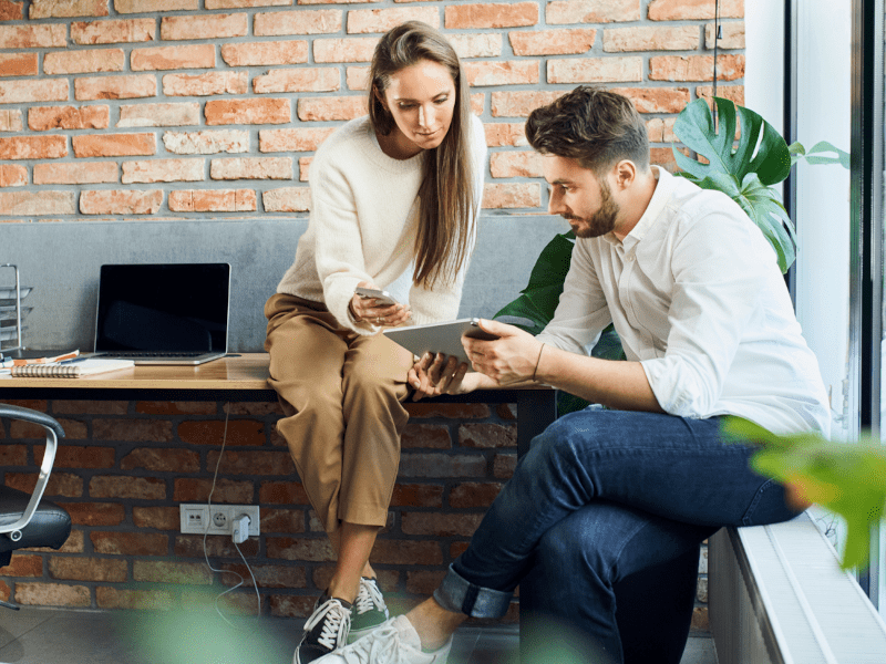 Zwei Personen tauschen sich über ein Tablet aus – Sinnbild für aktive Zusammenarbeit und Wissensaustausch in einer digitalen Kundencommunity.