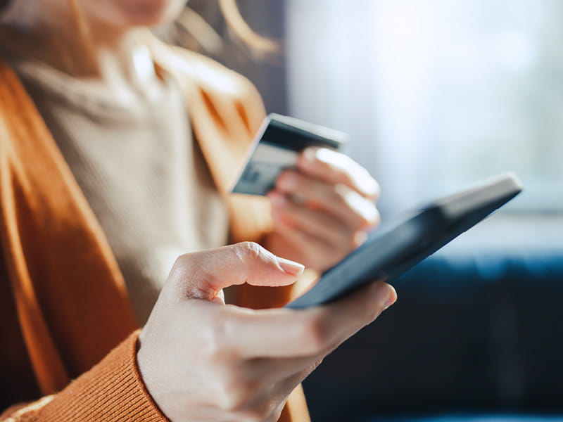 Person hält Smartphone und Bankkarte in den Händen beim digitalen Bezahlen