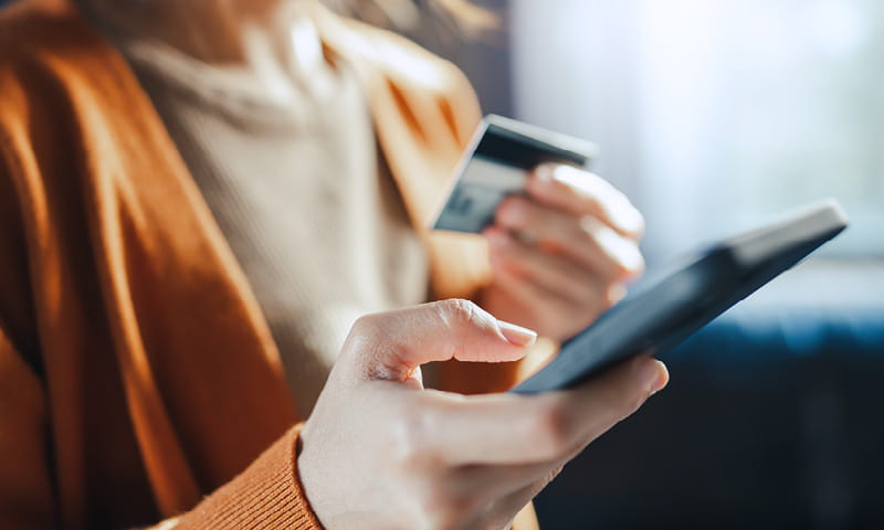 Person hält Smartphone und Bankkarte in den Händen beim digitalen Bezahlen