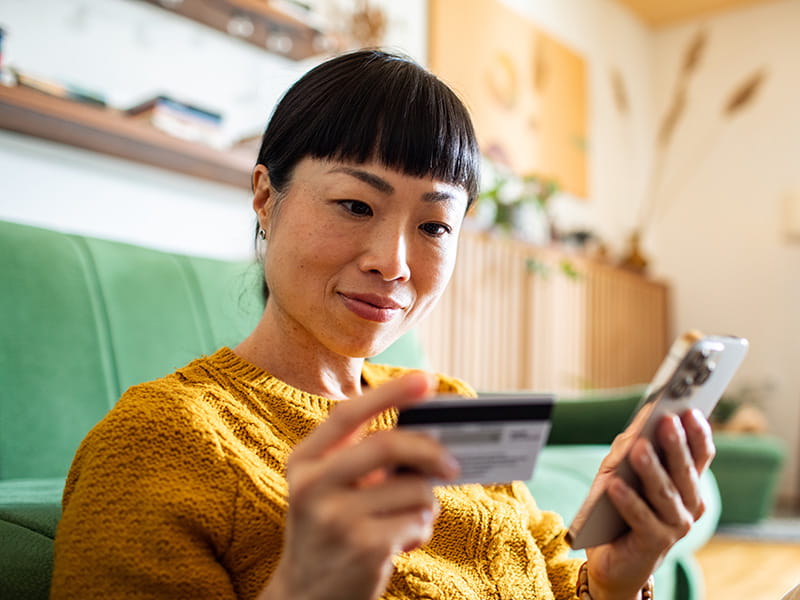 Frau hält Smartphone und Bankkarte in den Händen für digitales Bezahlen