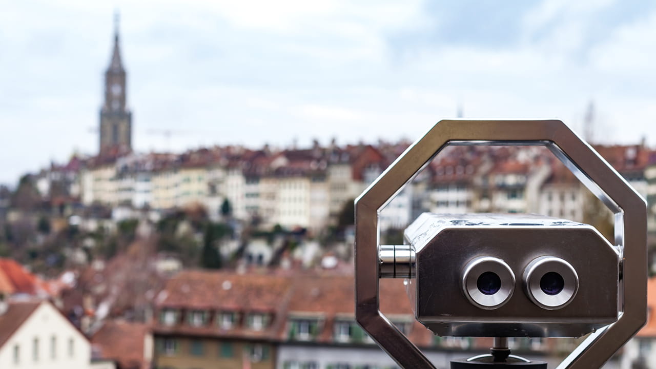 Aussicht über die Berner Altstadt mit Fernrohr im Vordergrund und unscharfer Stadtkulisse im Hintergrund.